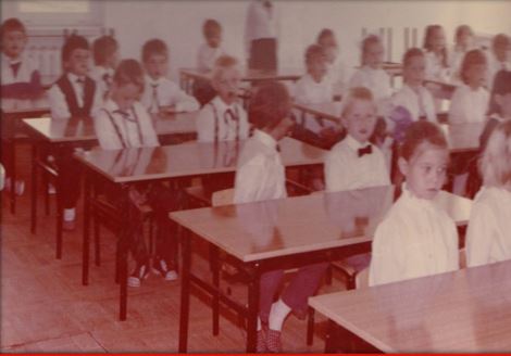 Patron i historia - uczniowiew galowych strojach siedza w ławkach w nowej sali SP 330.