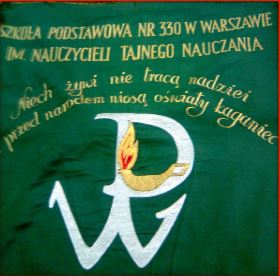 Patron i historia - zdjęcie przedstawia sztandar SP 330. Na zielonym tle widnieje nazwa szkoły oraz wyhaftowany napis "Niech zywi nie tracą nadziei przed narodem niosą oświaty kaganiec"