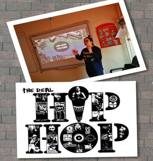 Uczniowskie Forum Naukowe - uczennica na tle tablicy multimedialnej opowiadajaca o kulturze hip-hopu.